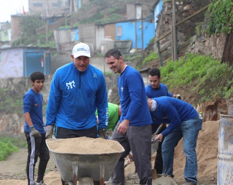 Braulio (white cap) helping to build a community wall to prevent mudslides from engulfing the homes in the background